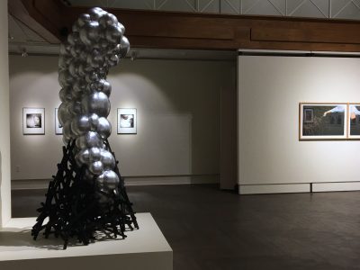 Partial gallery view of the 2020 Faculty exhibition. Sculpture in foreground and prints in background.
