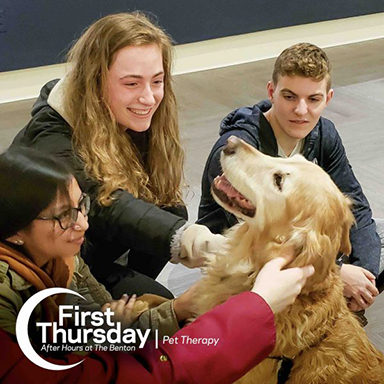 Students playing with dog on First Thursday.